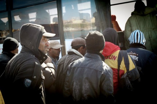 Migrantes da Tunísia, após quatro dias no mar, pegam ônibus em Lampedusa que os levaria a um centro de detenção